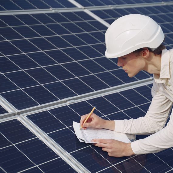 Businessman in a white helmet near solar battery